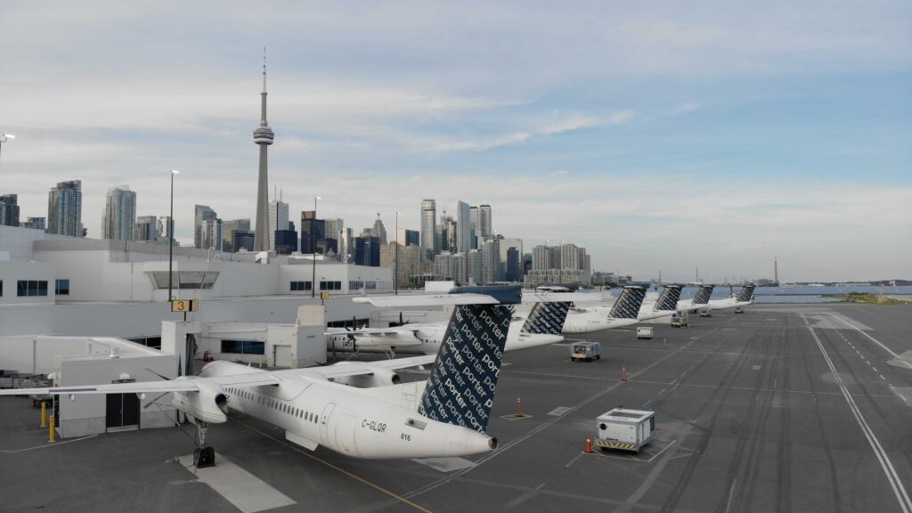 Des avions à l’Aéroport Billy Bishop, avec le panorama de Toronto à l’arrière-plan.