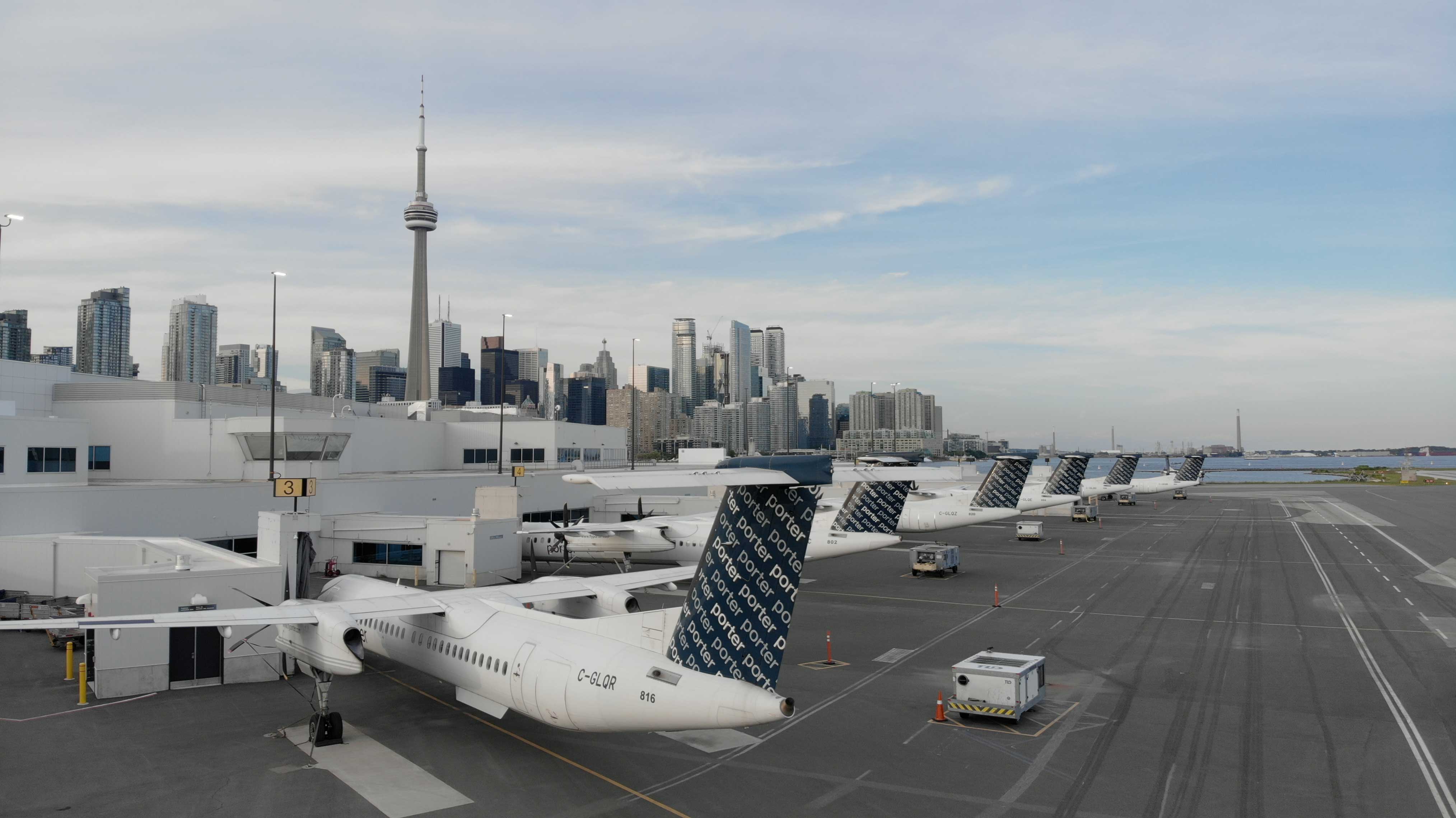 Des avions à l’Aéroport Billy Bishop, avec le panorama de Toronto à l’arrière-plan.
