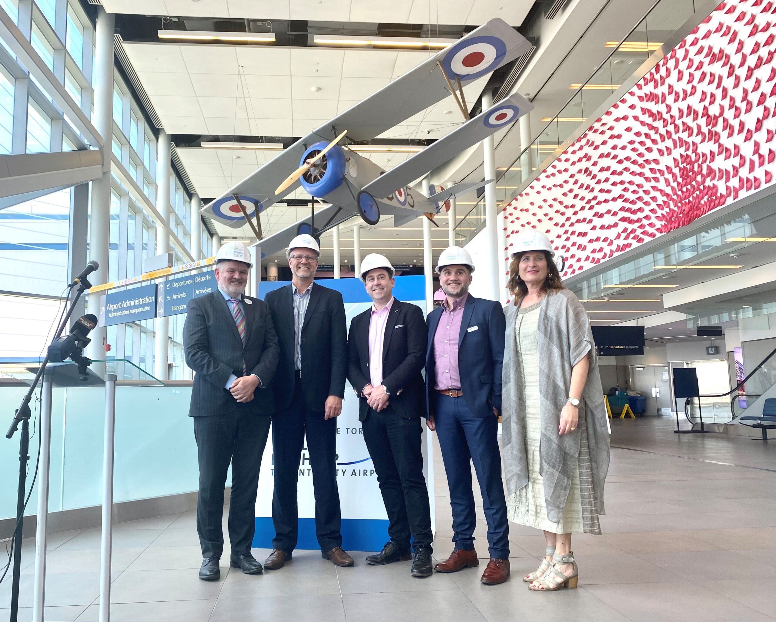 Des représentants se rassemblent sous la maquette de Nieuport dans l’atrium de l’aéroport.