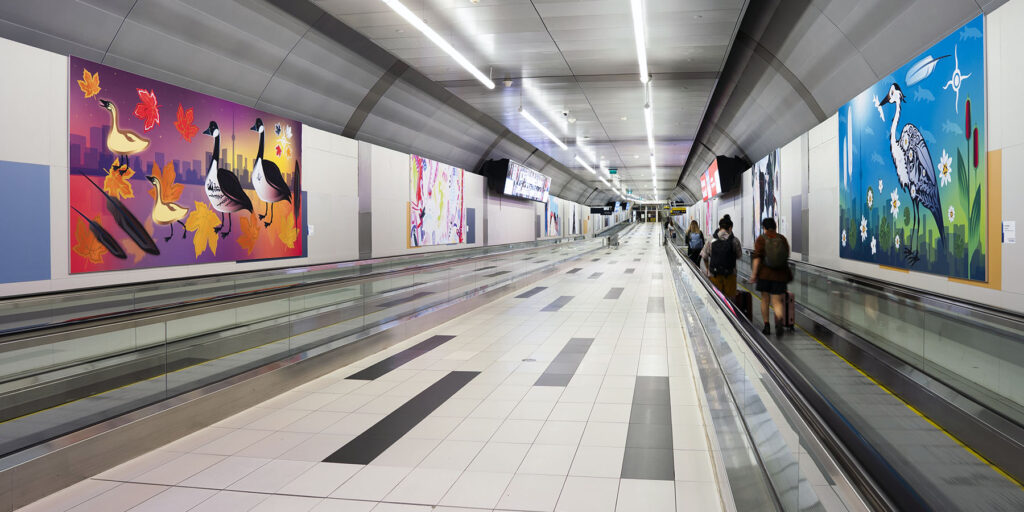 Des œuvres colorées du programme Perspectives bordent le tunnel piétonnier de l’aéroport.