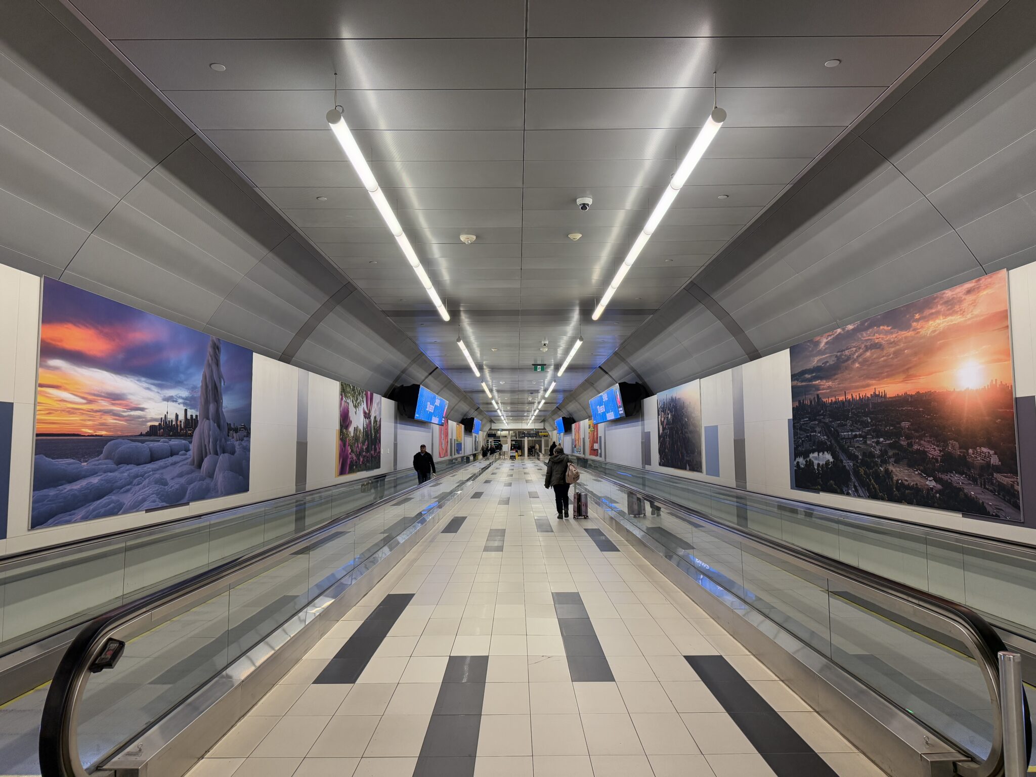 Œuvres exposées le long du tunnel piétonnier de l’aéroport.