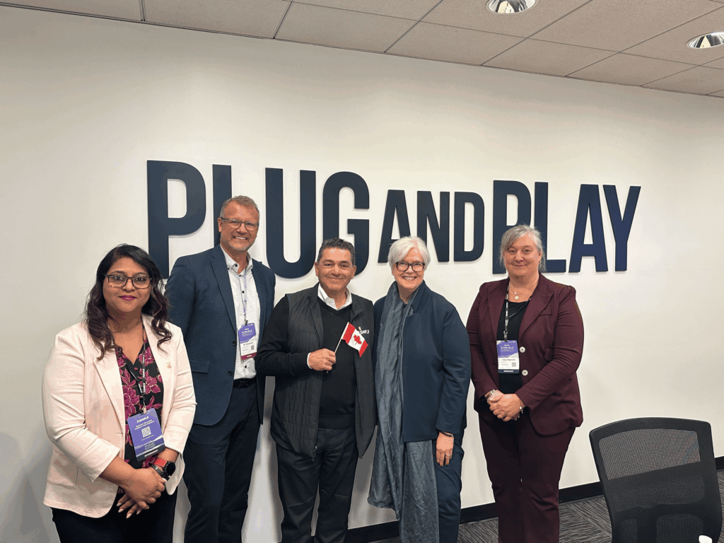 Des représentants posent devant le logo de Plug and Play.