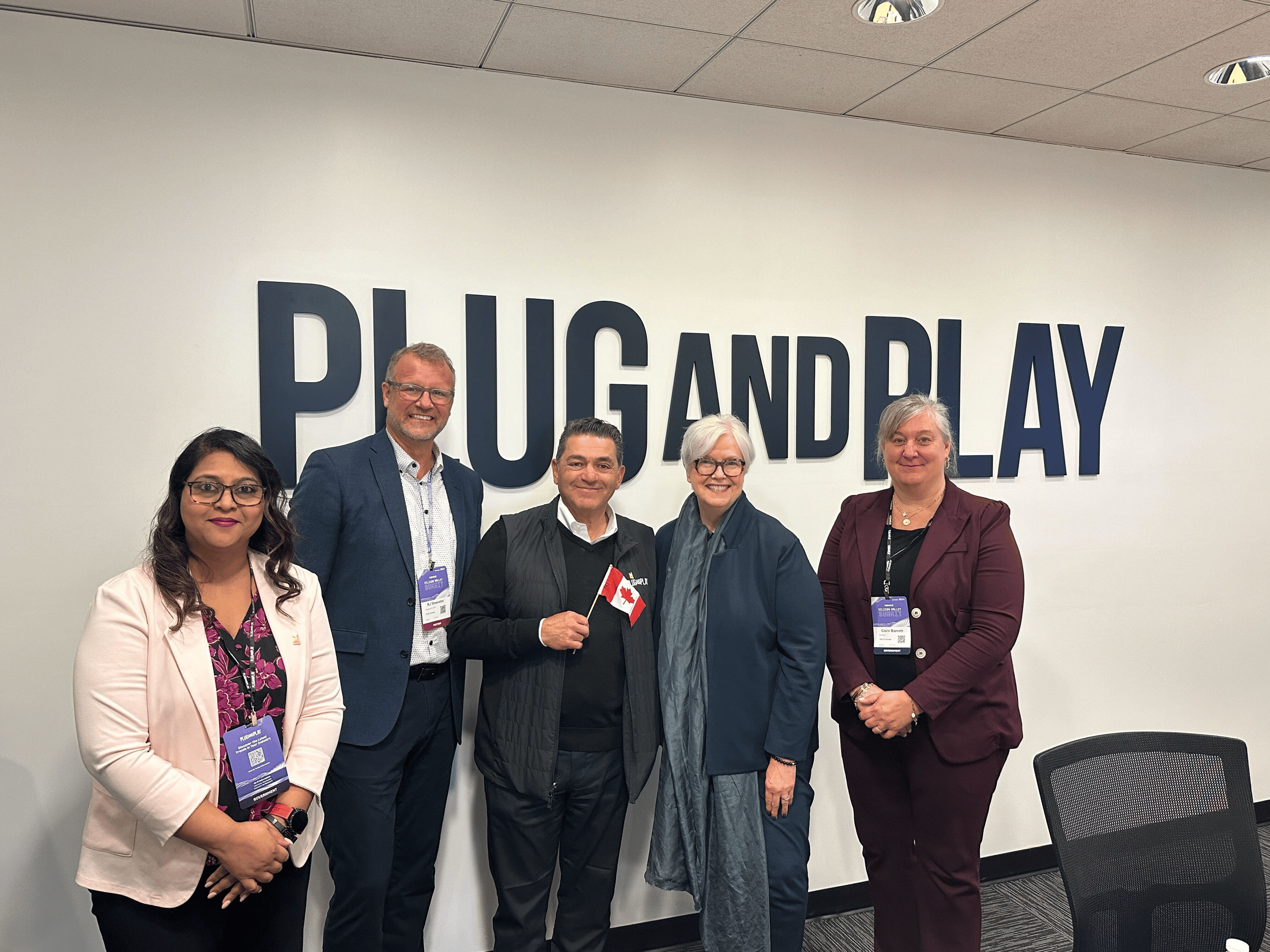 Des représentants posent devant le logo de Plug and Play.