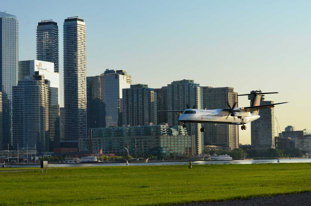 Des avions à l’Aéroport Billy Bishop, avec le panorama de Toronto à l’arrière-plan.