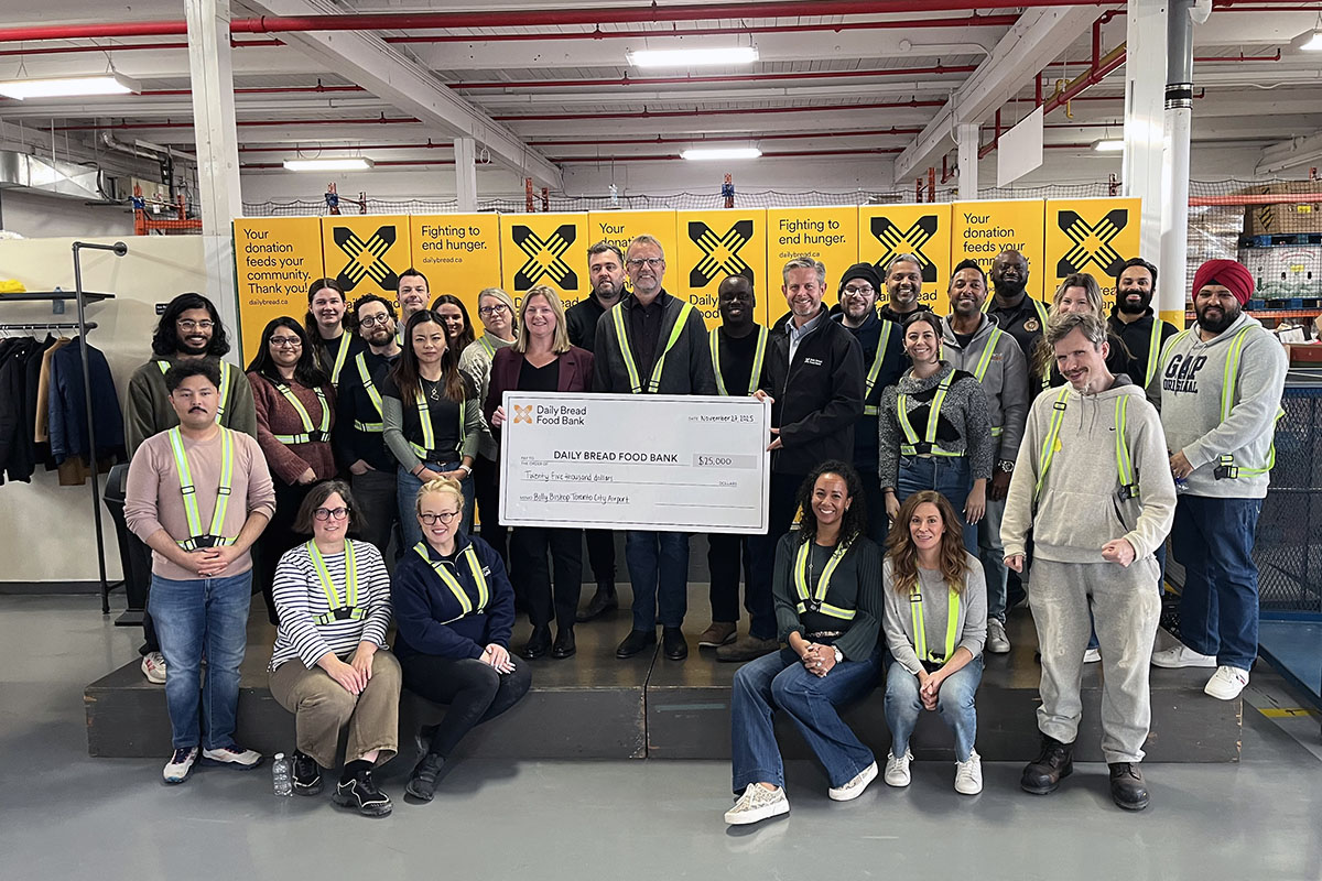 Des membres de l’équipe de l’aéroport présentent un chèque de don à la banque alimentaire Daily Bread.