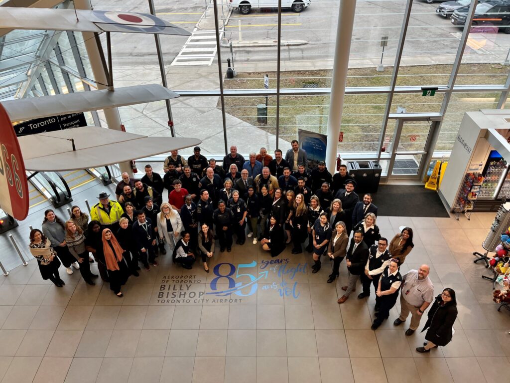 Un groupe se rassemble dans l’atrium de l’aéroport pour son 85e anniversaire.